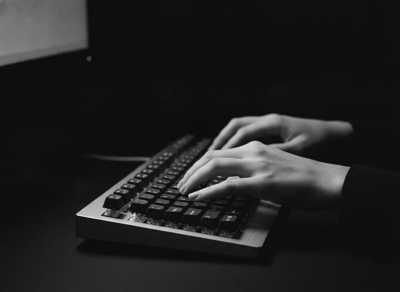 Des mains sur un clavier dans la pénombre