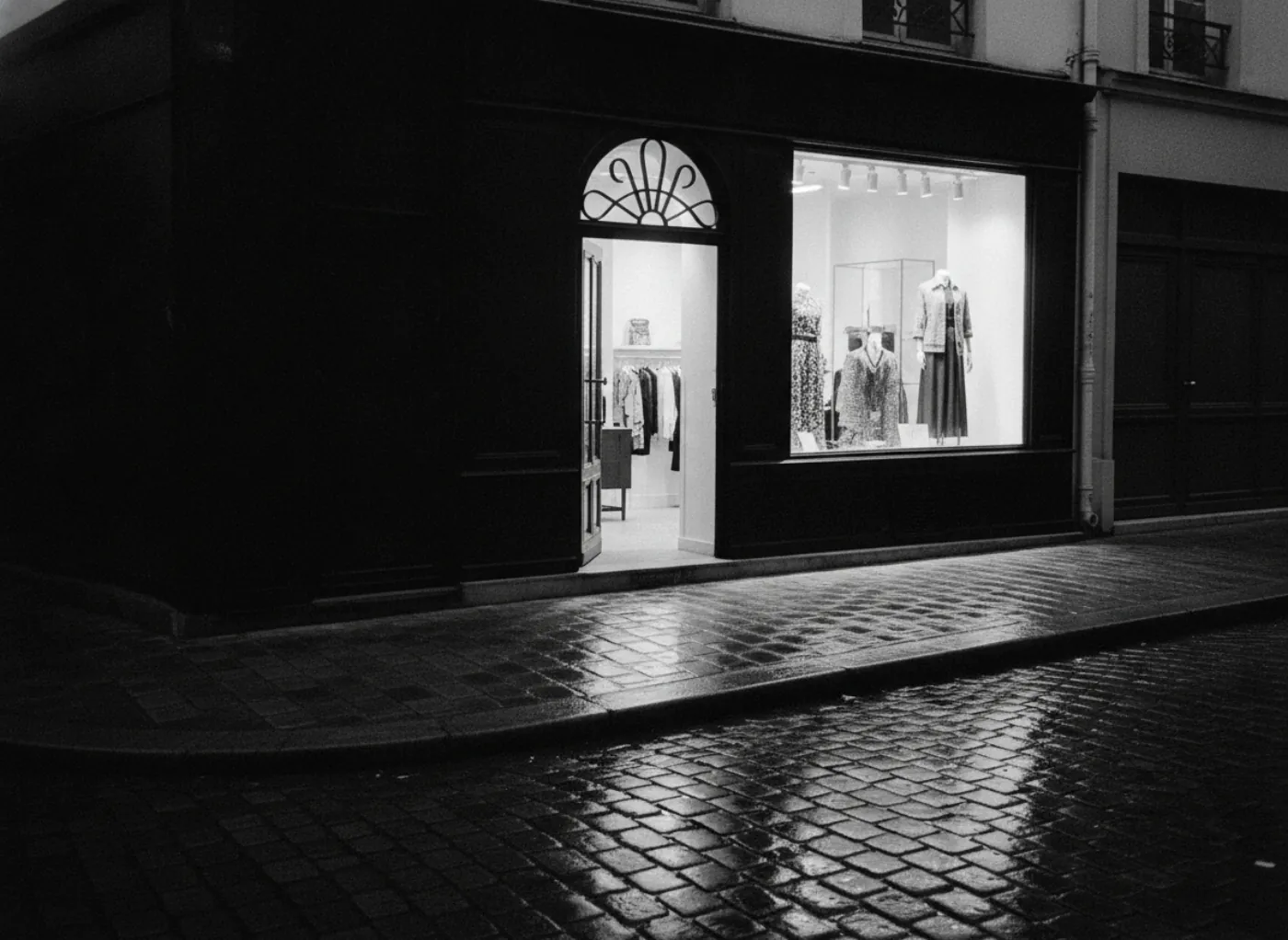 Une devanture éclairée de l'intérieur, le soir, dans une rue pavée